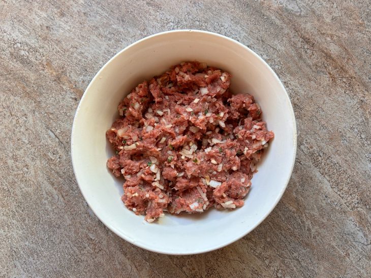 carne moída para bolinho misturada com as mãos para integrar os temperos.
