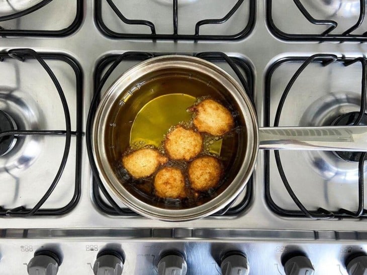 Uma panela com os bolinhos sendo fritos no óleo.