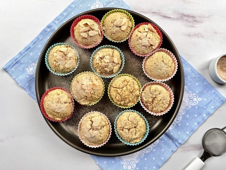 Uma forma com vários bolinhos de chuva crus polvilhados com canela.