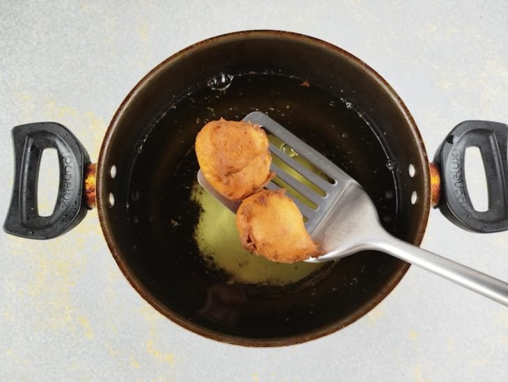 Bolinhos sendo fritos e virados no óleo até ficarem dourados por fora.
