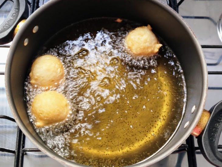 Bolinhos de chuva fritando em panela com óleo.