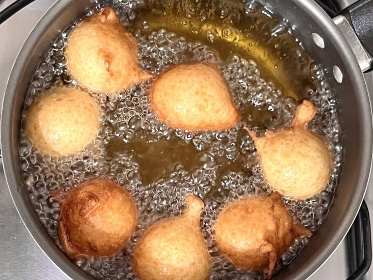 Uma panela contendo óleo quente fritando bolinhos de chuva.