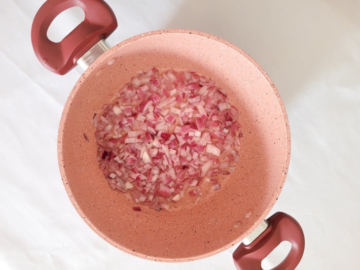 Uma panela com cebola roxa picadinha refogada.