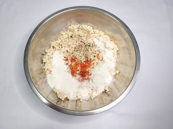 Um recipiente com a feijão triturado, pimenta, cominho, farinha e sal.