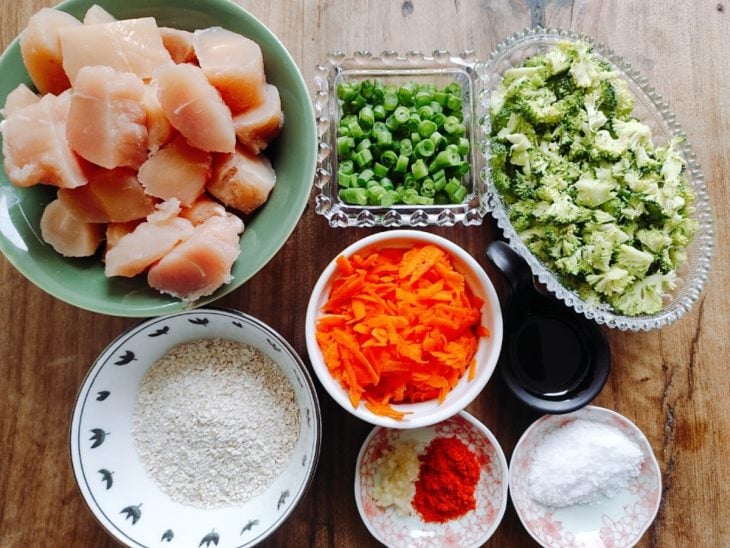 Ingredientes para a receita de bolinho de frango com legumes separados em uma bancada.
