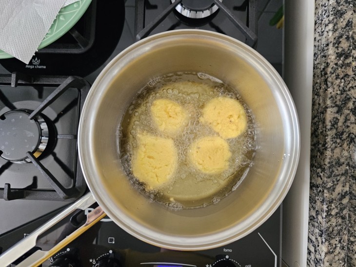 Bolinhas da massa fritando em óleo quente.