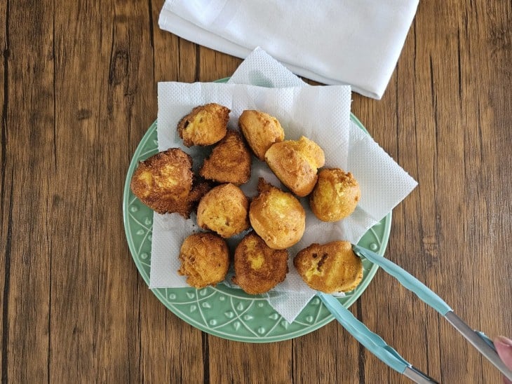 Bolinhos de fubá frito em cima de um prato com papel toalha.