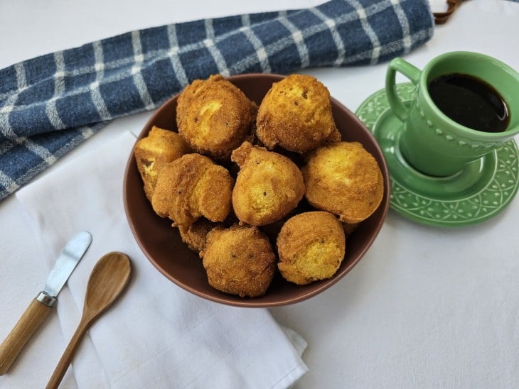 Bolinhos de fubá frito em uma tigela e café ao lado em uma xícara.