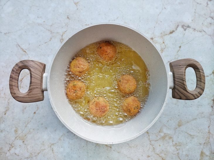 Bolinhos fritando em panela com óleo quente.