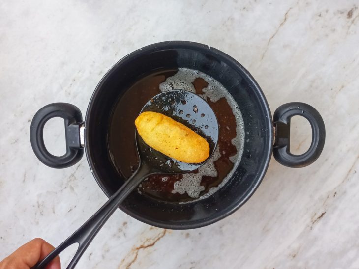 bolinho de mandioca com carne frito em óleo quente.