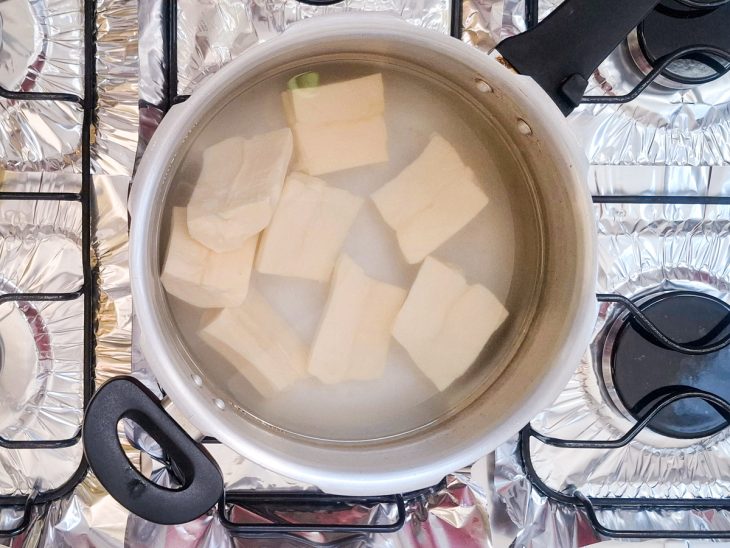 Mandiocas cozinhando em uma panela de pressão com água e sal.