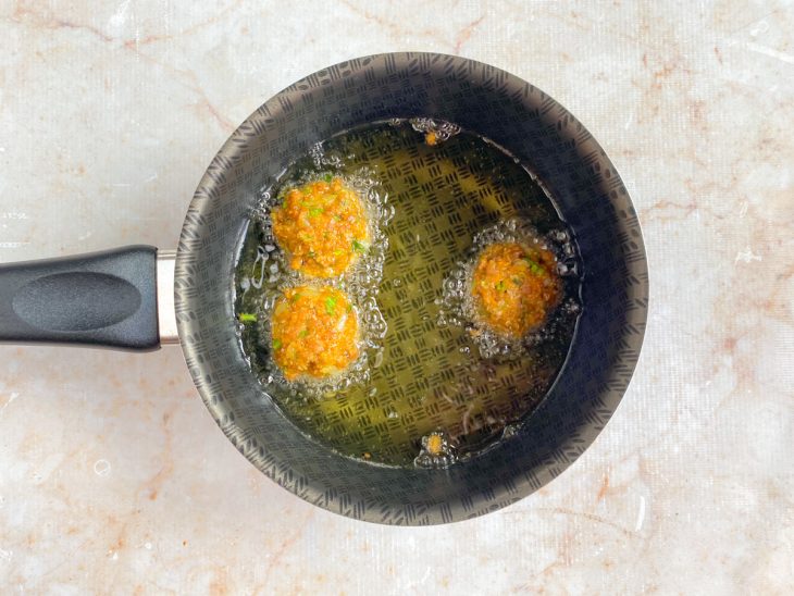 Panela com óleo e bolinhos fritando.