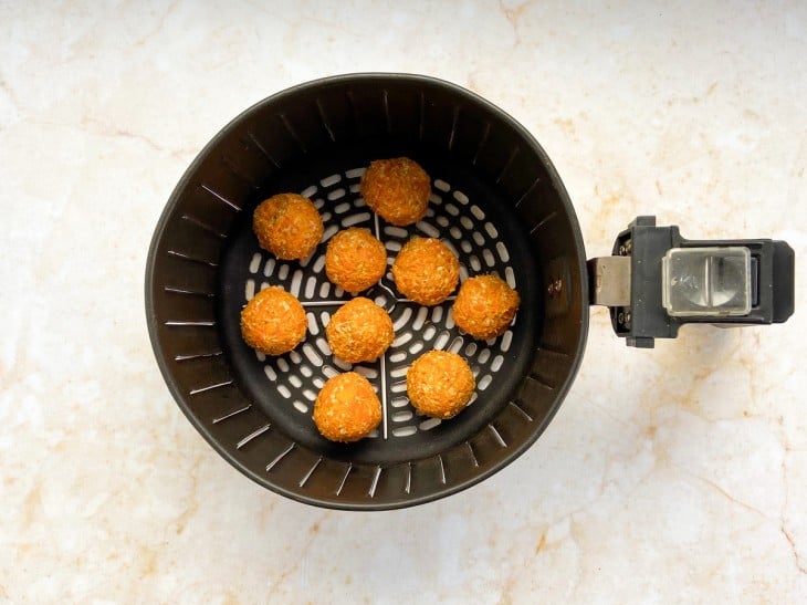 Uma cesta de air fryer contendo bolinhos de abóbora.