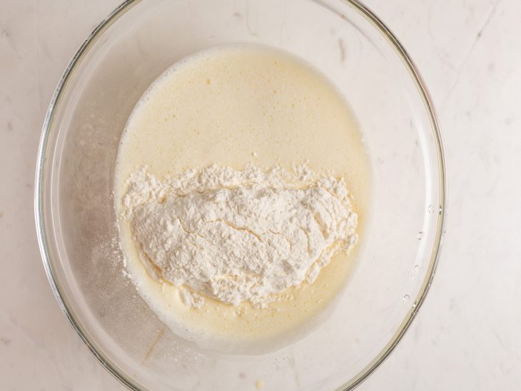 Mistura do liquidificador em uma tigela com farinha e fermento.
