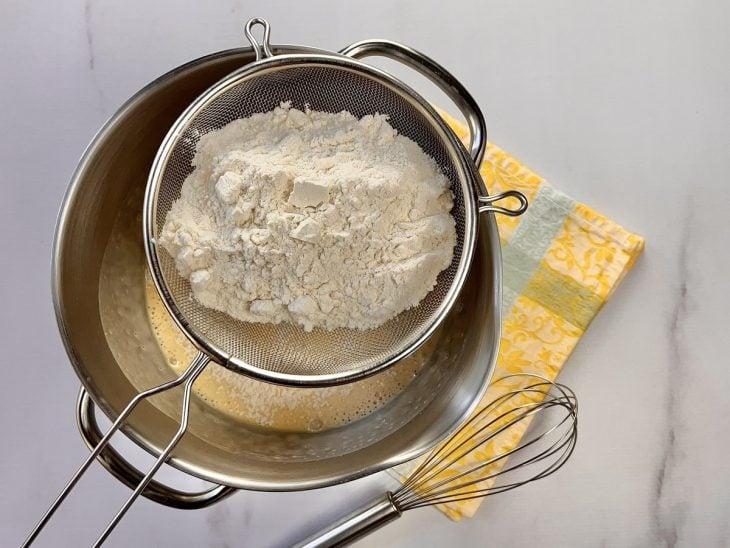 Um recipiente contendo a mistura de ovos, açúcar e farinha.