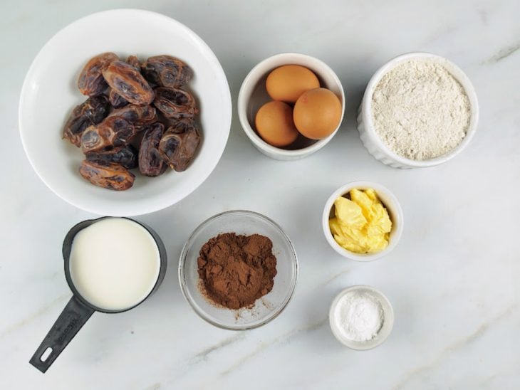 Ingredientes para a receita de bolo com tâmaras sem açúcar reunidos em uma bancada.