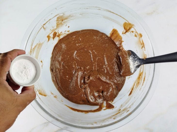 Mistura do liquidificador em uma tigela de vidro, incorporada com farinha de aveia e fermento.