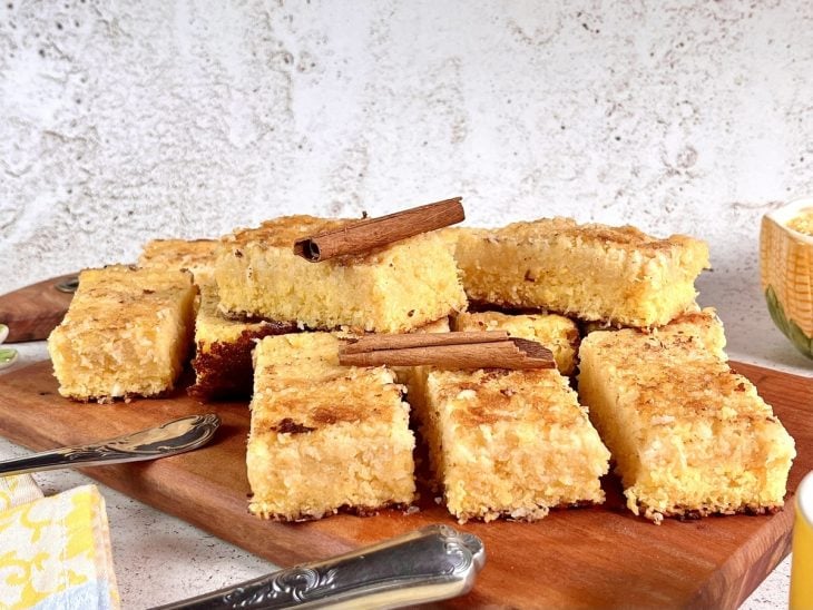 Uma tábua contendo bolo cremoso de flocão e coco.