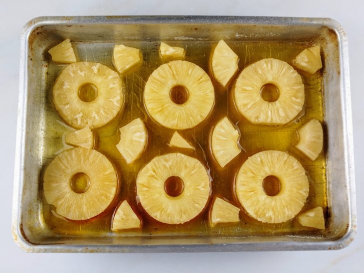 Rodelas de abacaxi distribuídas sobre o caramelo.