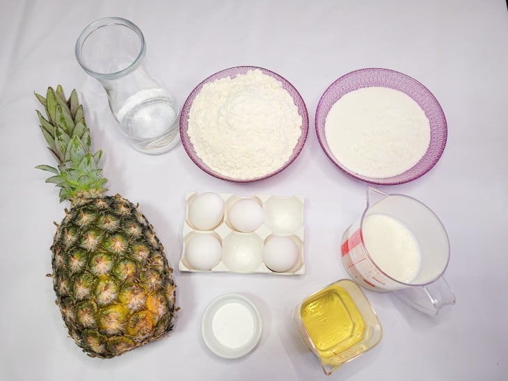 Ingredientes da massa e calda do bolo de abacaxi com coco reunidos.