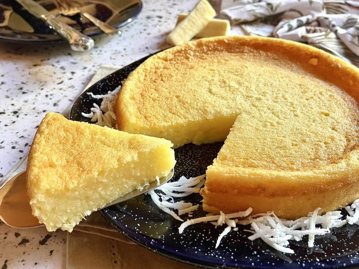 Bolo de aipim desenformado sobre um prato de cerâmica pronto para consumo.