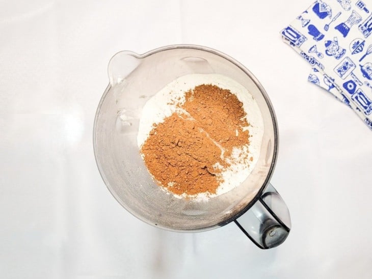 Um liquidificador com óleo, ovos, açúcar, chocolate, cacau e farinha.