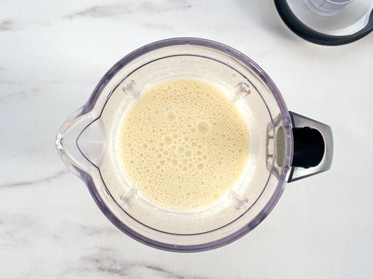 Um liquidificador com a mistura de ovos, açúcar, iogurte natural, arroz demolhado, o óleo e sal.