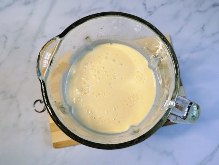Um liquidificador contendo a mistura de óleo, leite, açúcar, leite de coco e arroz cozido.