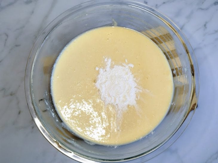 Um liquidificador contendo a mistura de óleo, leite, açúcar, leite de coco, arroz cozido, fermento e coco ralado.