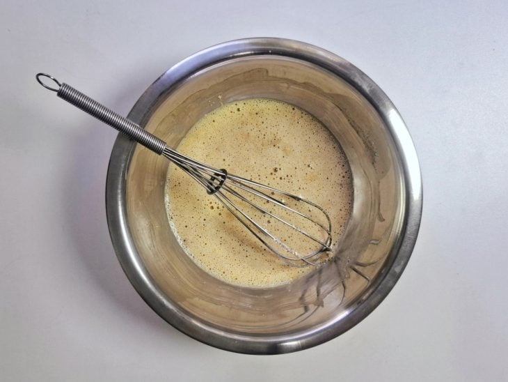 Gemas, farinha de aveia e aveia em flocos adicionados e incorporados em uma tigela redonda de inox.