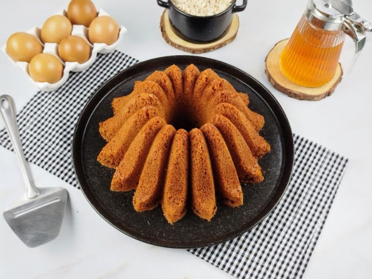 Bolo de aveia simples desenformado em um prato redondo preto.