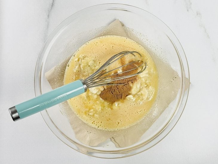 Ingredientes adicionados em uma tigela de vidro para serem incorporados com auxílio de um fouet (batedor de arame).