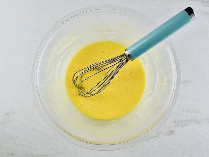 Açúcar, margarina e ovo batidos numa tigela.