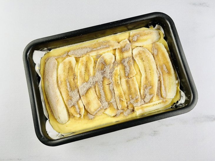 Massa, bananas, açúcar e canela colocados na forma.