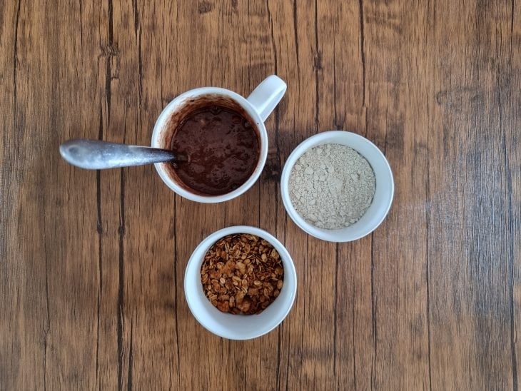 Caneca com ingredientes do bolo e outras duas trigelas com aveia e granola.