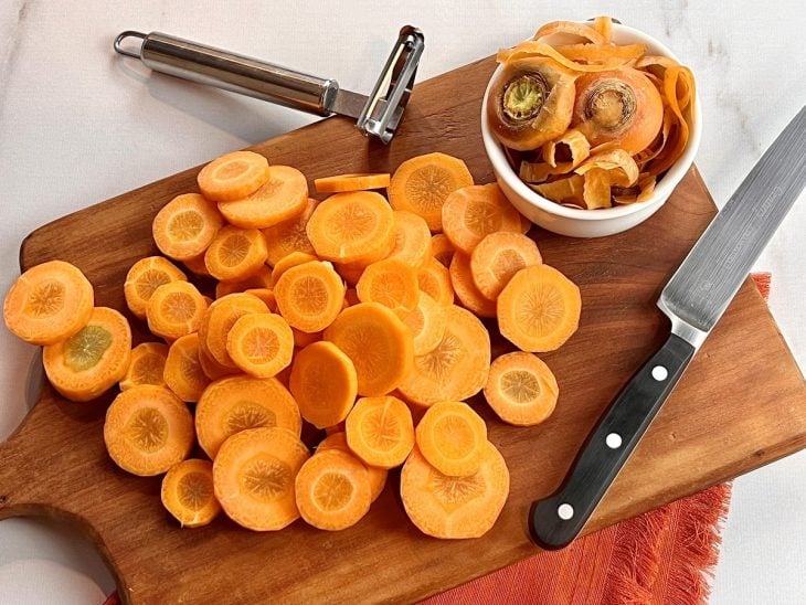 Uma tábua contendo cenouras cortadas em rodelas.