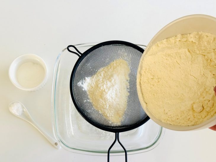 Ingredientes sendo peneirados em uma recipiente.