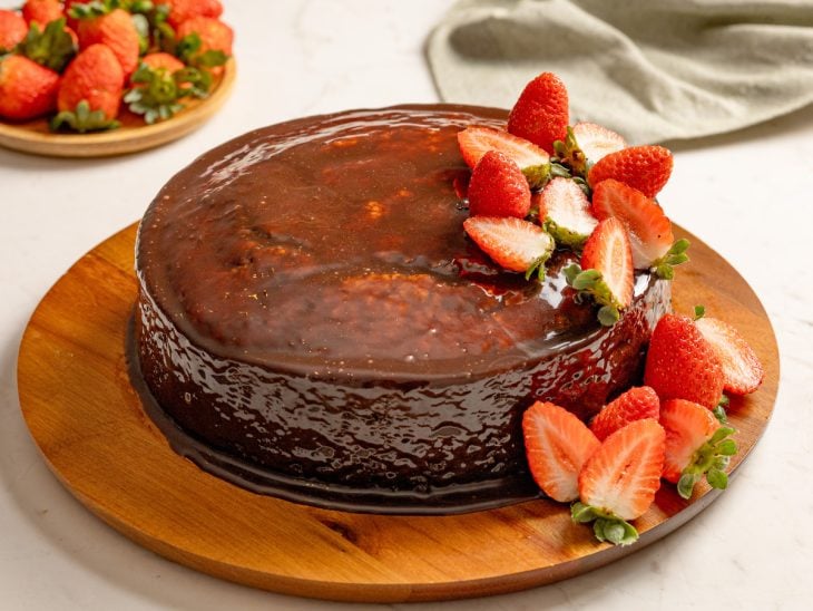 Bolo de cenoura com cobertura de chocolate e morango pronto para consumo.