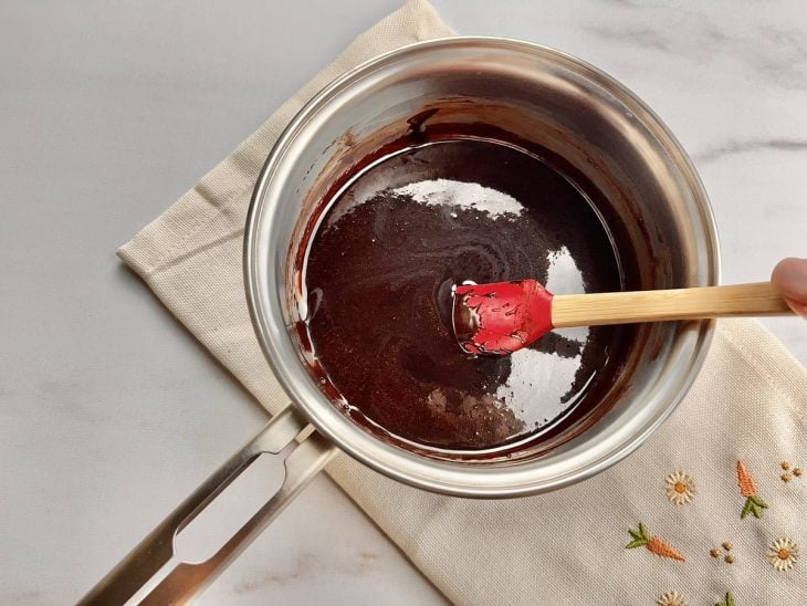 Uma panela contendo a mistura de açúcar, chocolate em pó, manteiga e leite.