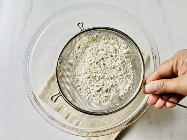 Ingredientes secos peneirados em uma tigela.