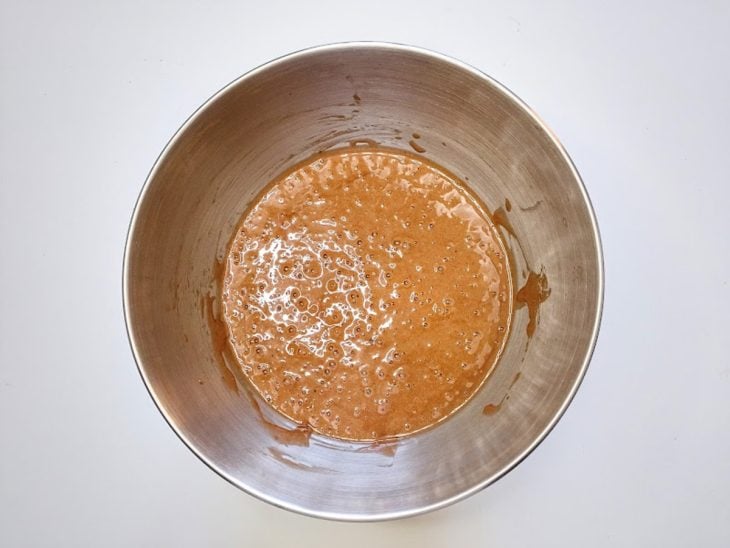 Um recipiente contendo a mistura de ovos, açúcar, baunilha, farinha, chocolate em pó e água.