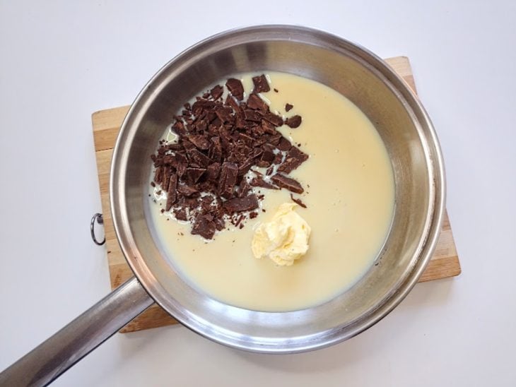 Uma panela contendo chocolate picado, leite condensado e manteiga.