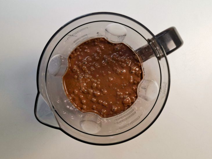 Bananas, ovos, azeite, baunilha e cacau sendo batidos no liquidificador.