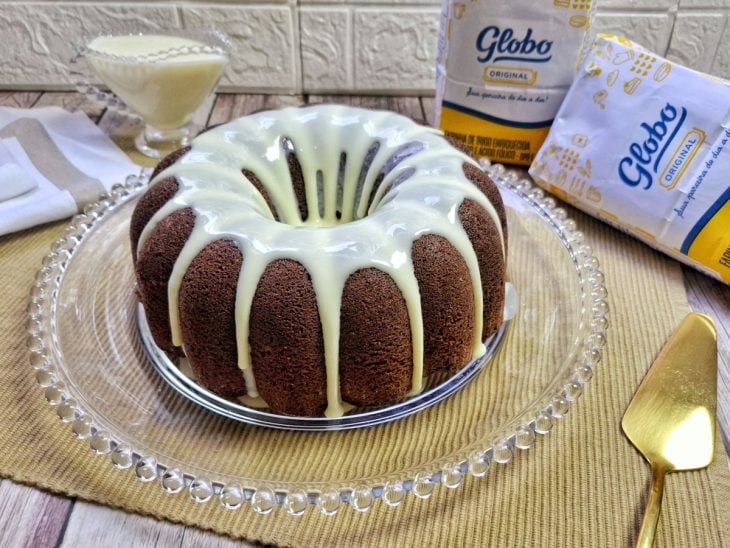 Uma boleira com o bolo de chocolate com cobertura de Ninho.