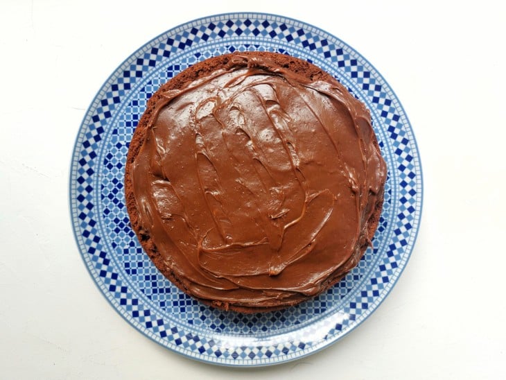 Um recipiente contendo bolo de chocolate com recheio de brigadeiro e morango sem decoração.