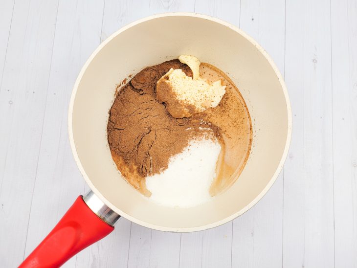 Uma panela contendo manteiga, chocolate em pó e açúcar.
