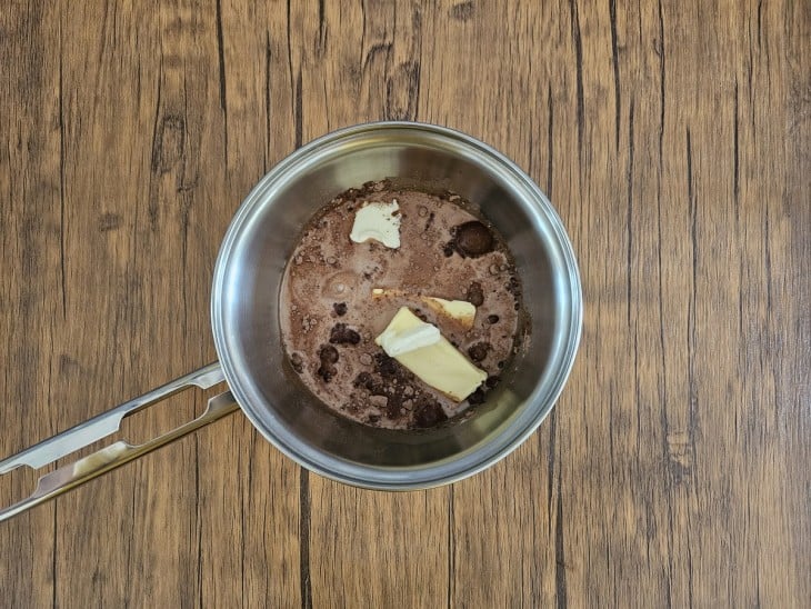 Uma panela com chocolate em pó, açúcar, manteiga e leite.