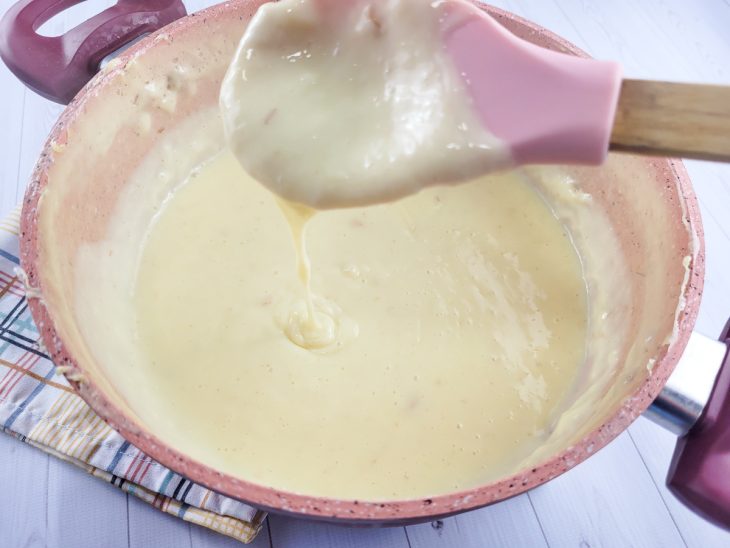 Colher mostrando o ponto cremoso do creme na panela.