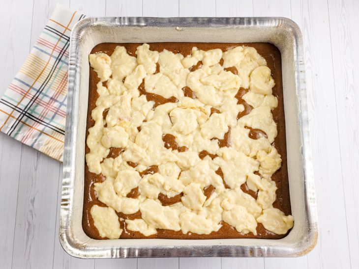 Massa de bolo com creme do recheio distribuído por cima.