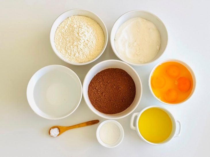 Ingredientes organizados na bancada com ovos, chocolate em pó e demais itens separados.